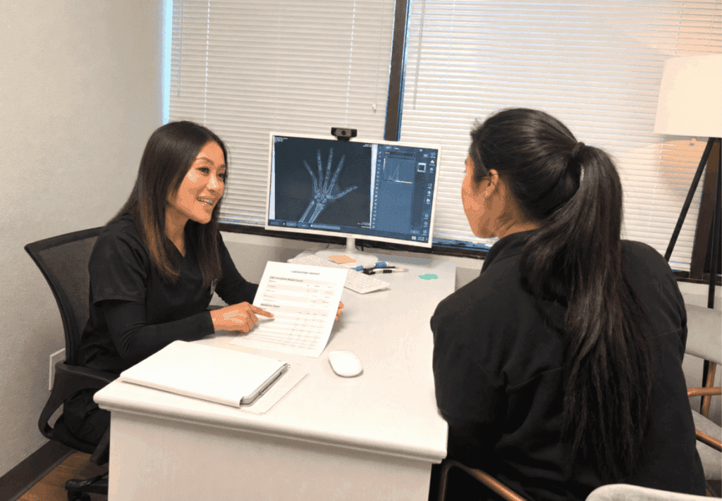 A pediatric growth specialist at I Grow Clinic reviewing a printed IGF-1 lab report with a parent during a consultation, explaining what the results mean for their child's growth potential.