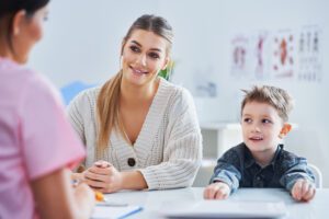 A mother and child meeting with a pediatric clinician to discuss growth hormone treatment options and costs.