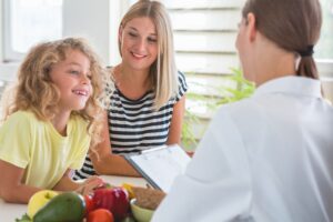 Pediatrician talking with a mother and child about healthy eating for better growth.