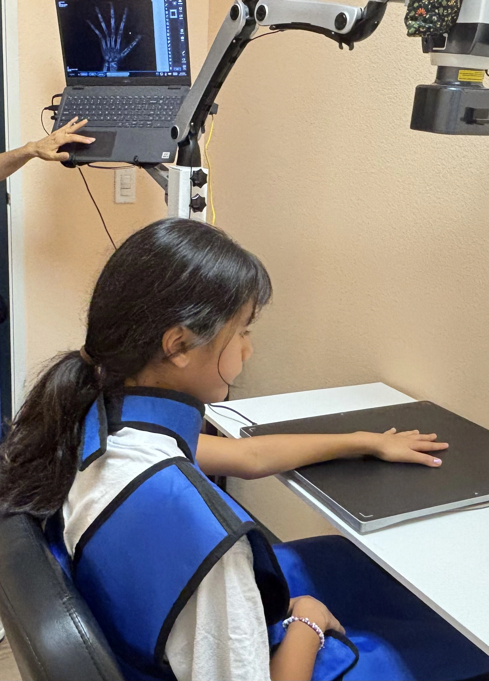 Child receiving a hand X-ray to assess bone age and growth potential during supervised growth hormone therapy, part of safe medical monitoring for balanced development.