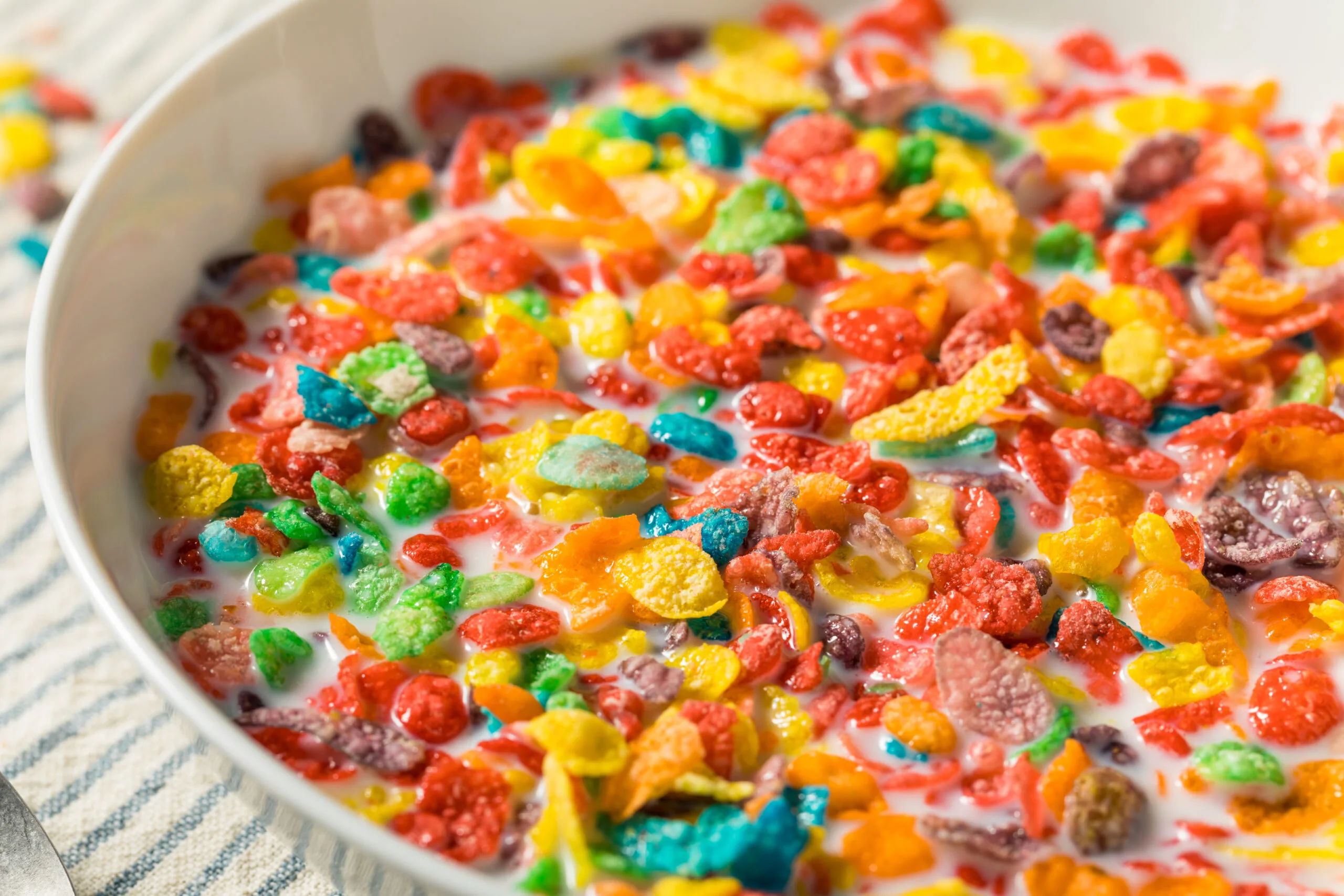 Colorful sugary breakfast cereal in milk, showing artificial dyes and high sugar content.