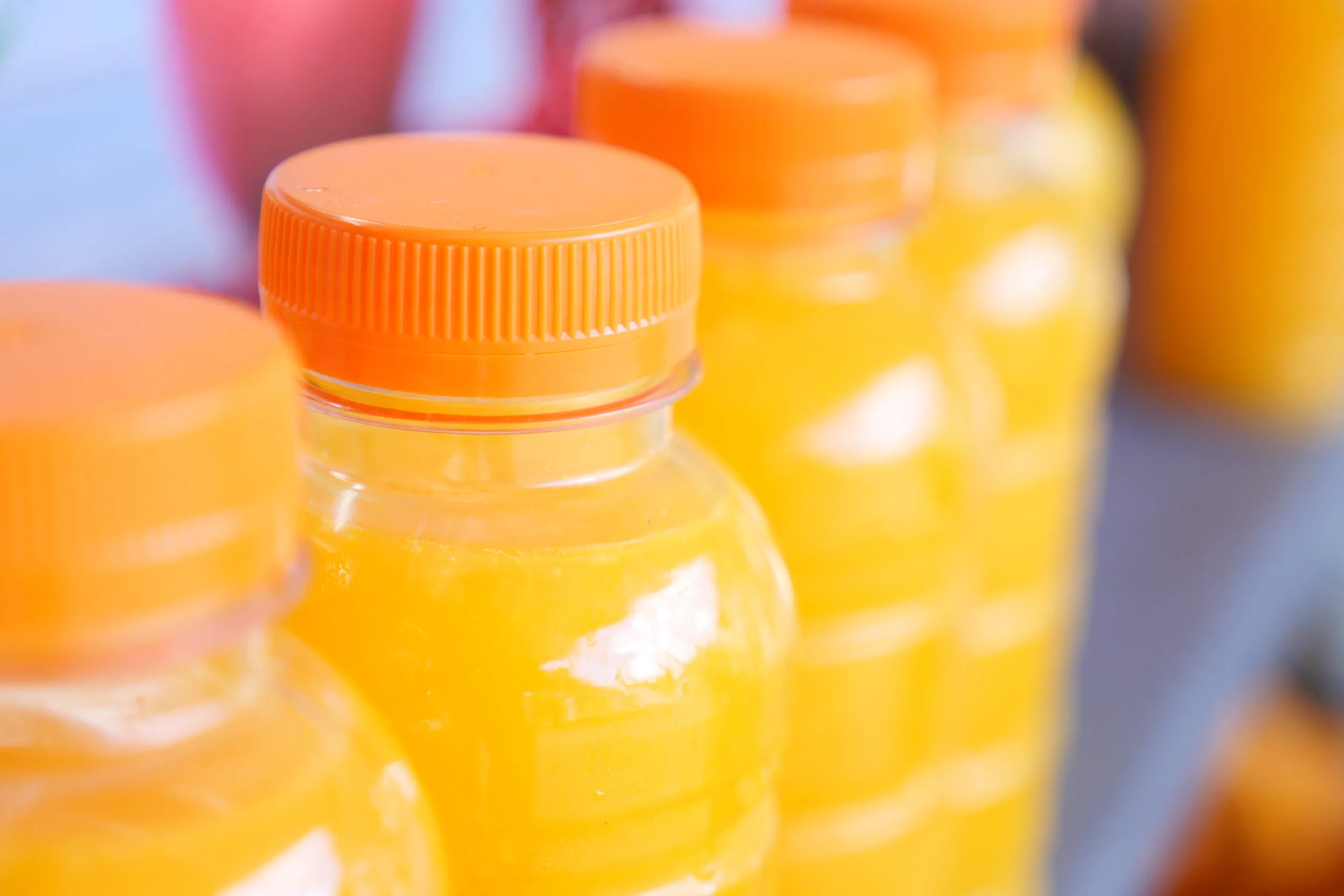 Bottles of orange fruit juice showing high sugar content compared to whole fruit with natural fiber.
