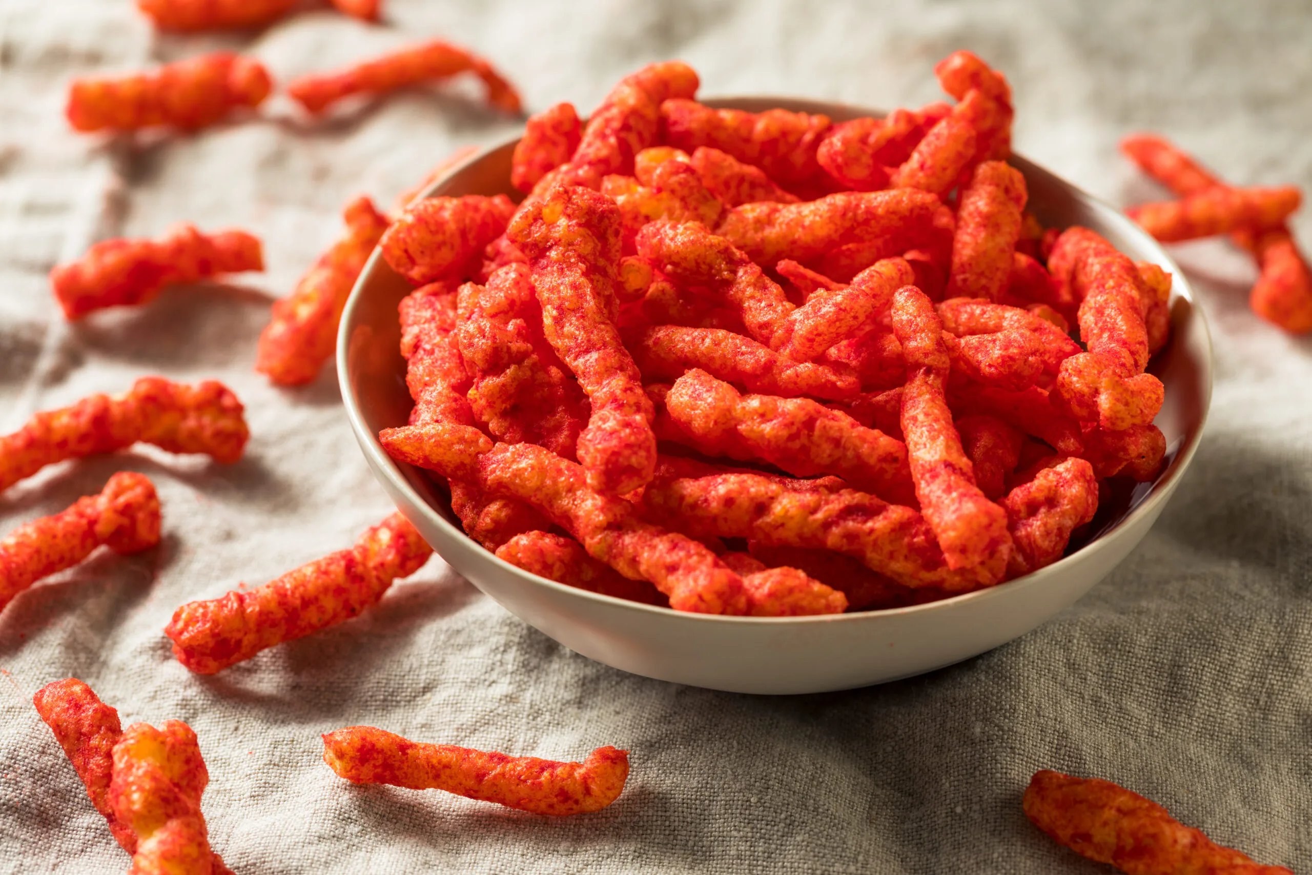 Bowl of bright red packaged snacks high in salt and additives that may interfere with healthy growth.
