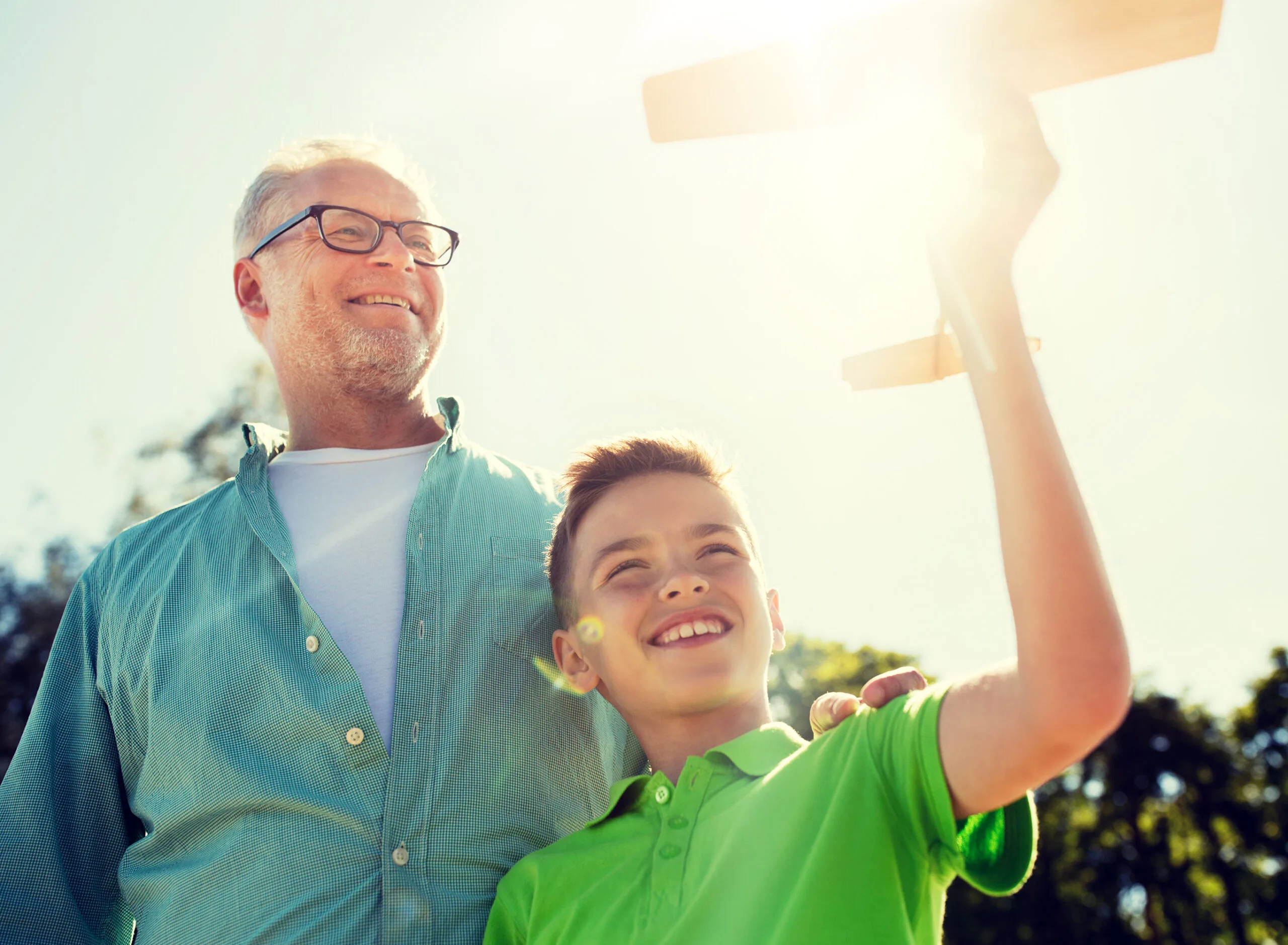 A smiling boy holding a wooden toy airplane beside his father, symbolizing confidence, hope, and the brighter future that thoughtful growth hormone therapy can help nurture.