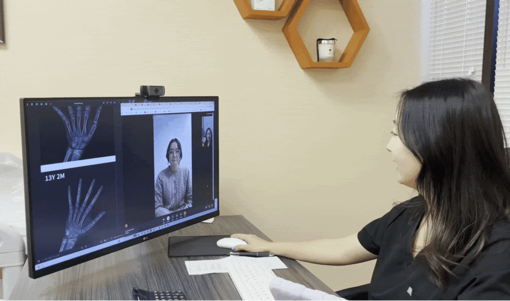 An I Grow Clinic nurse practitioner conducting a telehealth consultation with a patient, reviewing a hand X-ray bone age analysis on screen during a virtual growth evaluation appointment.