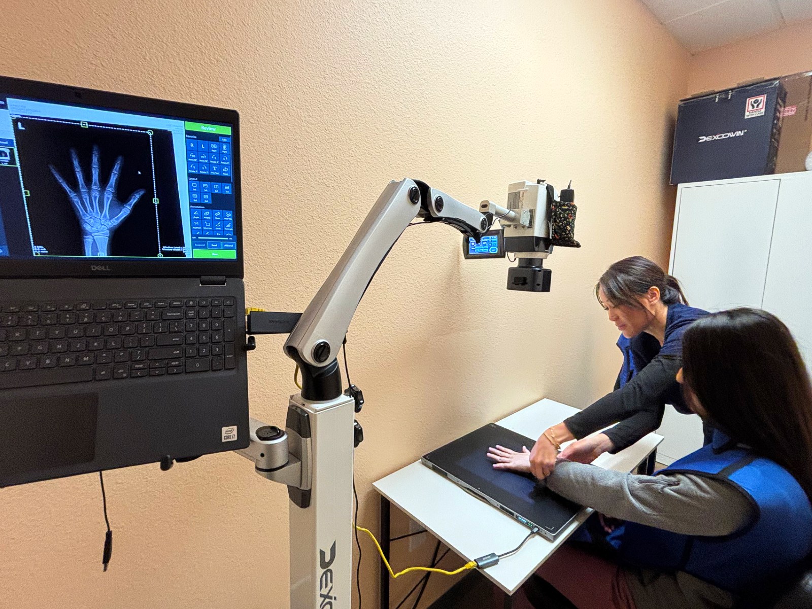 Provider positioning a child's hand for a bone age X-ray with the scan displayed live on screen