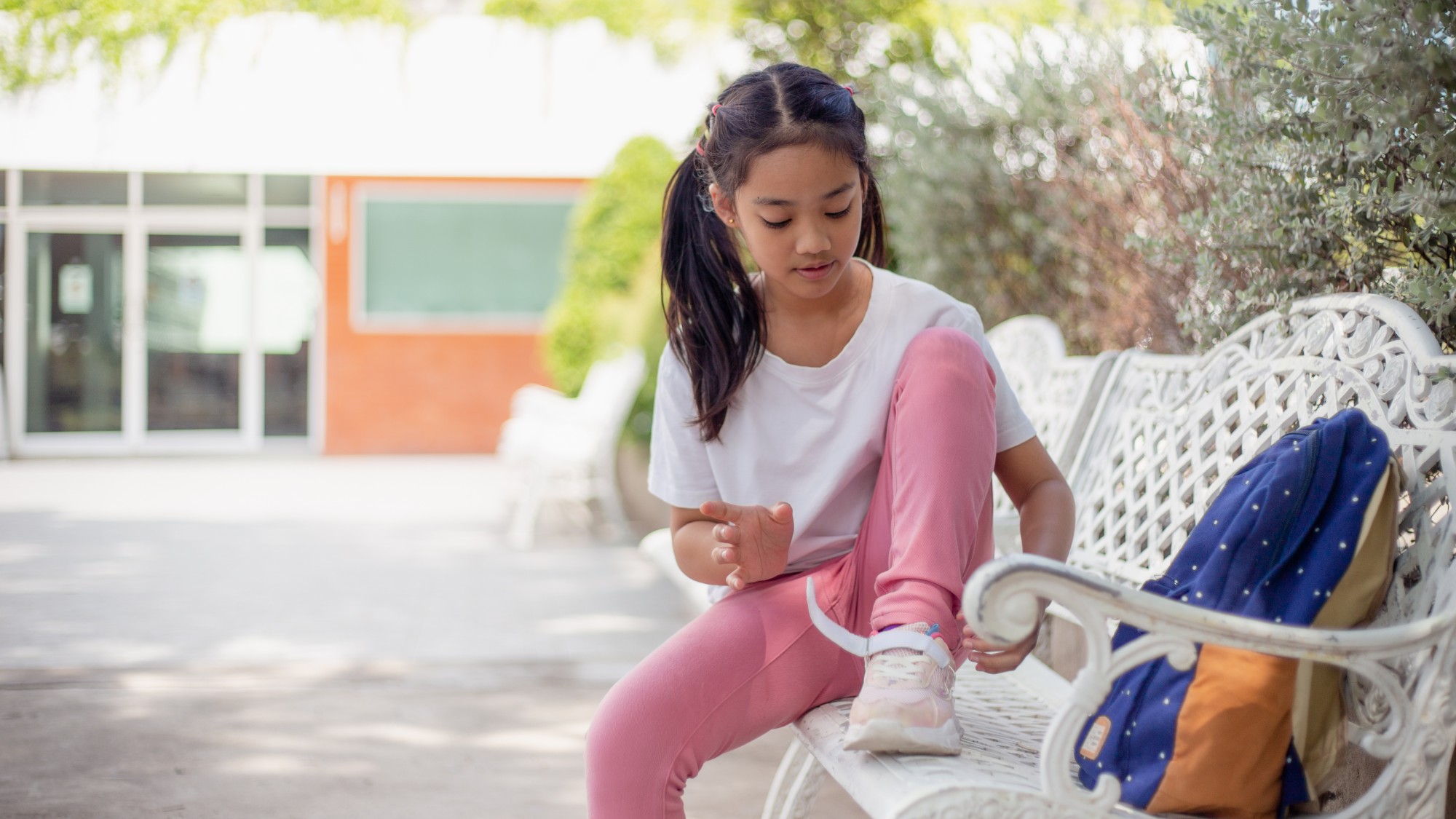 Preteen girl adjusting her sneaker on a bench, as outgrown shoes are a common growth spurt sign